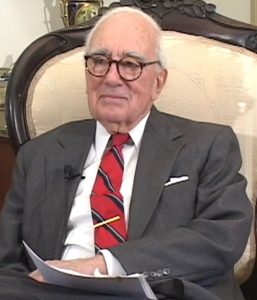 Hon. George Martin Cochran seated in a chair wearing a suit and tie.