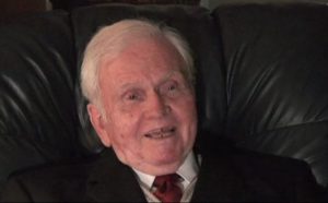 W. Carrington Thompson speaking during the 2007 interview. He is seated in a leather chair wearing a suit and tie.