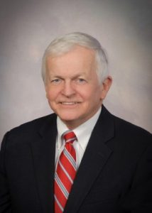Professional headshot of Walter S. Felton, Jr. He is in front of a grey backdrop wearing a suit and red striped tie.